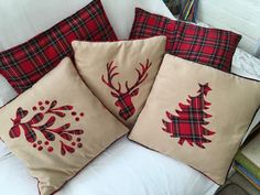 three pillows with christmas designs on them sitting on a white couch in front of a bookcase