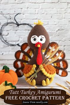 a crocheted turkey sitting next to two pumpkins on top of a table