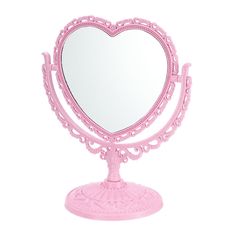 a pink heart shaped mirror sitting on top of a table