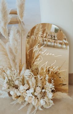 an image of a wedding card with flowers and feathers in front of a mirror on the floor