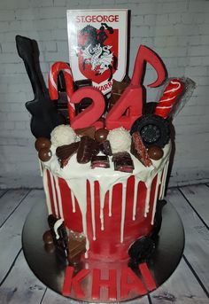 a red and white cake with chocolate candies, candy, and letters on it