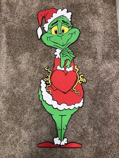 the grinch is wearing a santa hat and holding a heart