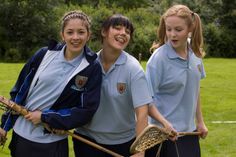 three girls in blue shirts holding lacrosse sticks