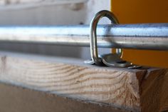 a close up view of a metal bar on a wooden structure with a yellow door in the background