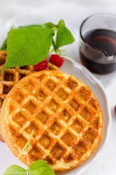 waffles with raspberries and syrup on a white plate