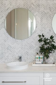 a bathroom with two round mirrors above the sink and a potted plant next to it