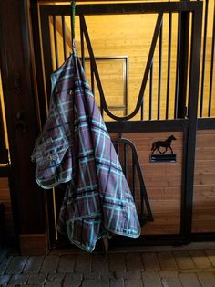 an umbrella is hanging on the side of a door with a horse in the background