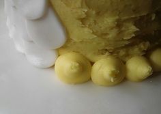 some yellow desserts are on a white plate and one is frosted with icing