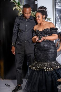 a man and woman dressed in black standing next to each other at a formal event