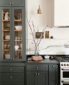 a kitchen with black cabinets and white counter tops, gold trim on the glass doors