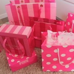 pink and white gift bags with bows on the top are sitting on the floor next to each other