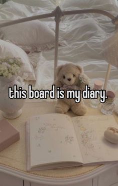 a teddy bear sitting on top of a bed next to an open book