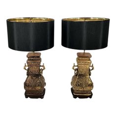 a pair of lamps sitting on top of a table next to each other with black shades