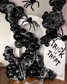 black balloons and spider decorations are on display in front of a trick or treat sign