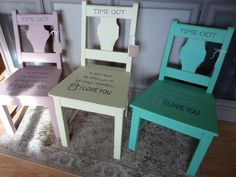 three wooden chairs with words painted on them sitting in front of a wall and rug