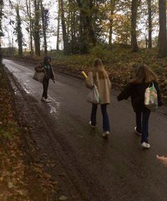 three people walking down the road in the woods