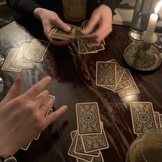 two people playing cards at a table with candles