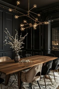 an elegant dining room with black walls and wooden table surrounded by chairs, chandelier and vase filled with flowers