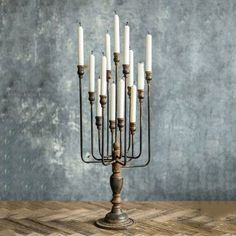 a tall metal candle holder with six candles in it's center on a wooden table