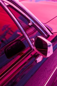 the side view mirror of a car with pink and purple paint on it's windows