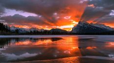 the sun is setting over a mountain lake with ice and snow on it's surface