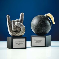 two black and white trophies with one holding a peace sign