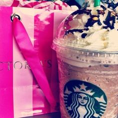 a starbucks drink with whipped cream and chocolate sprinkles on it next to pink shopping bags