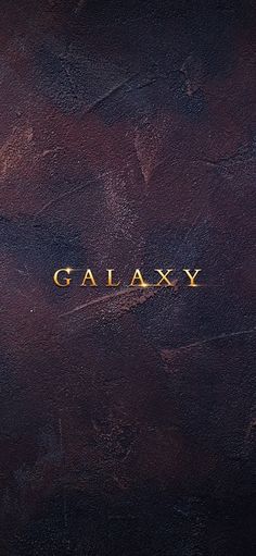 the word galaxy is written in gold on a brown leather surface with some dark colors