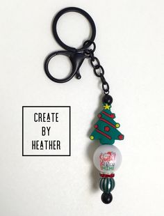 a keychain with a christmas tree on it and a button that says create by heather