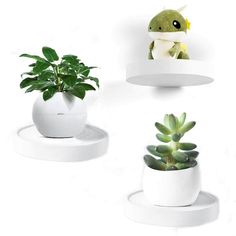 three white planters with plants in them sitting on the wall above each other, one is holding a stuffed animal