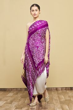 Purple kaftan-style tunic with one-shoulder, all-over bandhani print and asymmetric hem. Comes with nakshi embroidered white pant.
Components:2
Printed, Embroidered
Neckline:One Shoulder
Sleeve Length:Asymmetric
Fabric:Kaftan: Silk Bandhani; Pant: Cotton Satin
Color:Purple
Nakshi embroidery
Asymmetric hem
Scallop edged pant hem - Aza Fashions Latest Bandhani Dress Pattern, Bandini Outfits, Bandhani Outfits, Bandhani Outfit Ideas, Fusion Wear Indian, Bandhani Dress Pattern, Bandhani Kaftan, Bandhani Dresses, Purple Kaftan