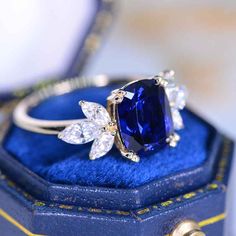 a blue ring sitting on top of a blue velvet box with gold trimmings