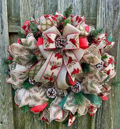 a christmas wreath with pine cones and bows hanging on a wooden door handle decorated with red, white and green fabric