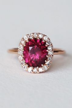 This rare pink-purple Umbalite brings me joy whenever I’m near it. Skillfully set in a tight low-profile multi prong design with a frame of post-consumer reclaimed single cut diamonds. Spiraling varied sized rubies enwrap the delicately crafted gallery for a dainty minimal design that yet packs a lot of gem power and vivacious energy. Umbalite is a new variety of Garnet that was discovered in Tanzania around 2015. Pink Lab-created Ruby Ring With Brilliant Cut, Pink Brilliant Cut Lab-created Ruby Ring, Pink Ruby Ring With Rose Cut Diamonds, Red Pink Sapphire Jewelry With Brilliant Cut, Red Brilliant Cut Pink Sapphire Jewelry, Fine Jewelry Ruby Halo Ring With Prong Setting, Ruby Gemstone Halo Ring With Round Cut, Ruby Halo Ring With Prong Setting, Ruby Halo Ring With Round Cut Gemstone