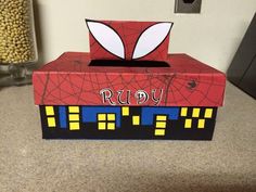 a cardboard box with a spiderman face on it sitting on a counter next to some cereal