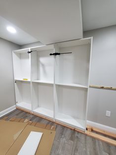 an empty room with white shelving in the middle and wood flooring on the other side