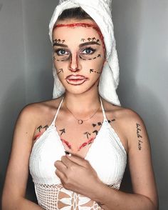 a woman with makeup on her face wearing a white towel over her head and writing all over her body