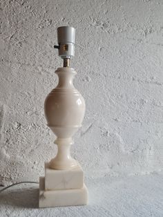 a white lamp sitting on top of a table next to a wall