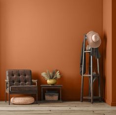 an orange room with a chair, stool and hat