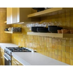 a kitchen with yellow tiles and white counter tops, pots and pans on the shelves