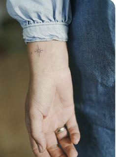 a person with a small star tattoo on their left wrist and the other hand behind them