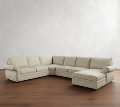 a white sectional couch sitting on top of a wooden floor