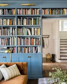 a living room filled with lots of books on top of a blue book shelf next to a couch