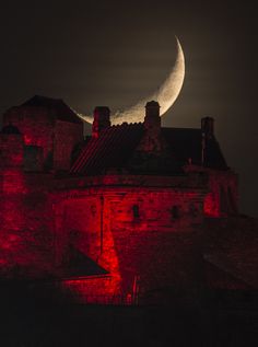 the moon is seen over an old castle at night