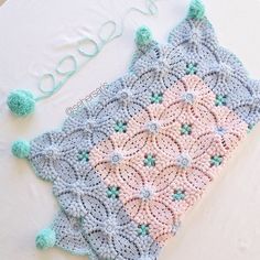 a crocheted blanket with pom poms on it