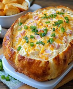 a cheesy bread dish on a plate with green onions and cheese in the background