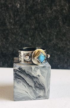 I handcrafted this silver ring and set a pretty square labradorite on top and two small silver balls on either side of the labradorite. I textured the silver band. I patinated the ring and then buffed off some of the patina to give the ring a two tone look.  1 Only **Size 8** -Labradorite 6mm square -925 Sterling Silver  I handcraft each piece of jewellery one piece at a time in my garden studio. Each piece comes wrapped in anti-tarnish paper and sat inside a paper box. Message me for any questi Unique Silver Labradorite Ring, Silver Labradorite Hand Forged Rings, Hand Forged Silver Labradorite Rings, Rings In Silver, Garnet Bracelet, Garden Studio, Textured Ring, Handcrafted Rings, Silver Jewelry Rings