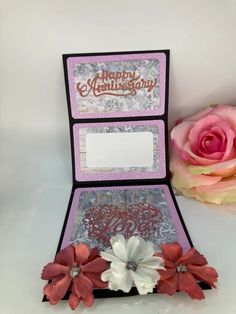 an open card box with flowers on it and a pink rose in the corner next to it