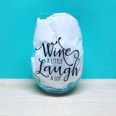 a wine glass with the words wine at little laugh on it's side, sitting against a blue wall