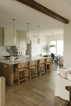 a kitchen and dining room with wood floors, white walls and wooden beams in the ceiling